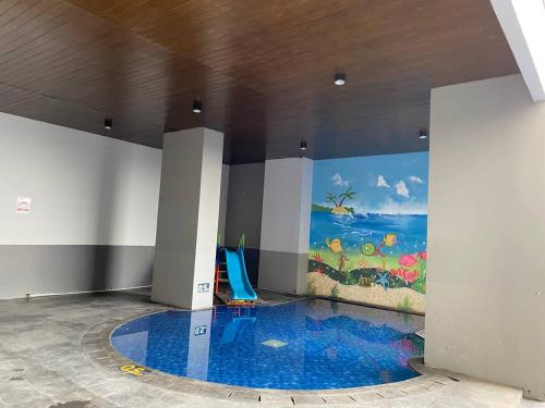 a room with a swimming pool with a painting on the wall at Tamansari Mahogany Apartment By Sagita Residence Karawang in Karawang