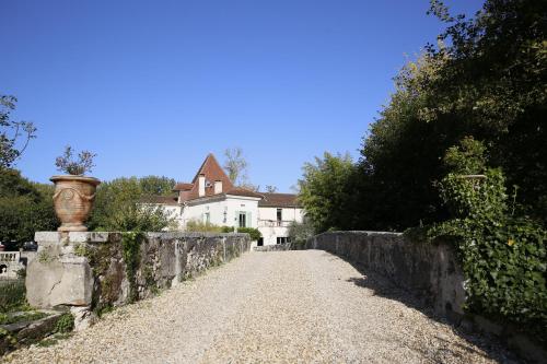 a dirt road with a stone wall and a house at Le Moulin de Saint-Aulaye in Saint-Aulaye