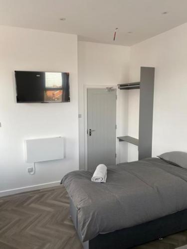 a bedroom with a bed and a television on the wall at The Glenbuck Hotel Anfield in Liverpool