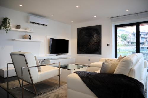 a living room with white furniture and a flat screen tv at Seaside XXI-10, By OP in Funchal