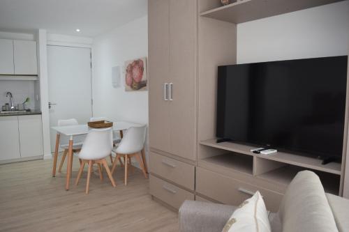 a living room with a television and a table with chairs at SYRAH Premium B1 - Vistas al Parque by depptö in Punta del Este
