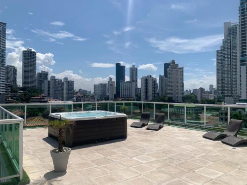 a rooftop patio with a hot tub and chairs on a city skyline at 4B - Centríco Divertido FIT 4BR in Panama City