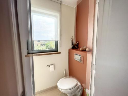 a bathroom with a toilet and a window at Suite de luxe avec espace salon et balnéo à la campagne in Opprebais