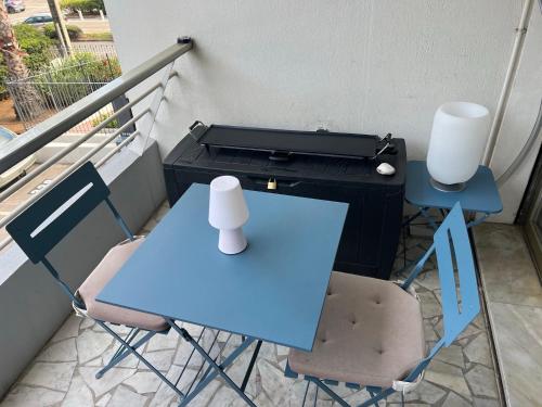 een blauwe tafel en stoelen op een balkon met een grill bij Seafront - beautiful flat with aircon and comfortable loggia in Vallauris