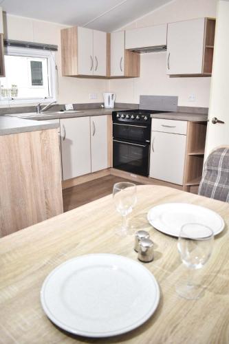 a kitchen with a table with two plates and glasses at Rio Gold LC20 in Minehead