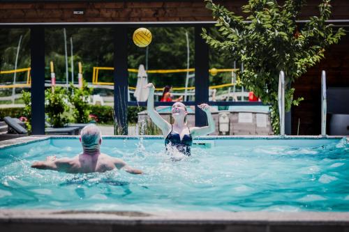 two people playing with a ball in a swimming pool at Mohácsi Wellness Vendégház és Lovasklub in Mohács