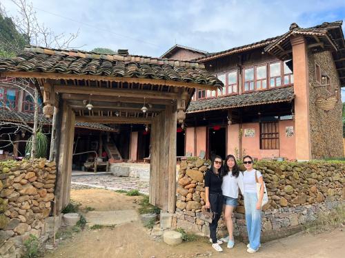 three women are standing in front of a building at Dinh Đá H'Mông - Karsterly Rock Lodge in Dồng Văn