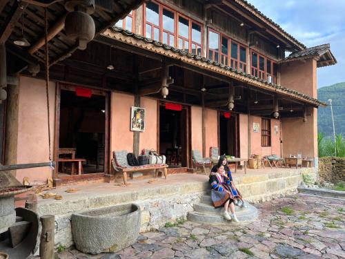 a woman sitting on the steps of a building at Dinh Đá H'Mông - Karsterly Rock Lodge in Dồng Văn