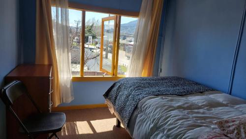 1 dormitorio con cama, ventana y silla en Pies a tierra, en Coyhaique