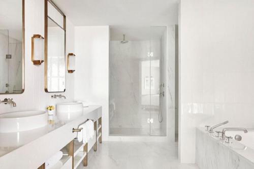 a white bathroom with two sinks and a shower at Four Seasons Hotel and Residences Fort Lauderdale in Fort Lauderdale