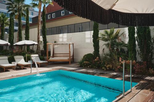 a swimming pool with chairs and an umbrella at GA Palace Hotel & Spa, a XIXth-Century Villa in Porto