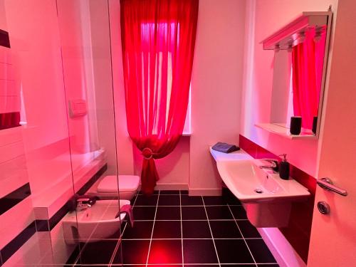 ein Badezimmer mit rosa Vorhängen, einem Waschbecken und einem WC in der Unterkunft Appartamento tranquillo BARCODE HOUSE in Erbusco