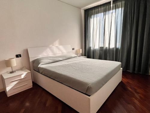 ein weißes Schlafzimmer mit einem großen Bett und einem Fenster in der Unterkunft Appartamento tranquillo BARCODE HOUSE in Erbusco