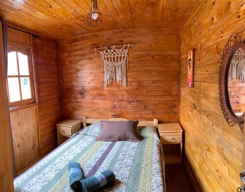 ein Schlafzimmer mit einem Bett in einer Holzhütte in der Unterkunft Cabaña Joshua in Puerto Iguazú