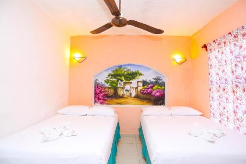 two beds in a room with a painting on the wall at Hotel Hacienda Cancun in Cancún