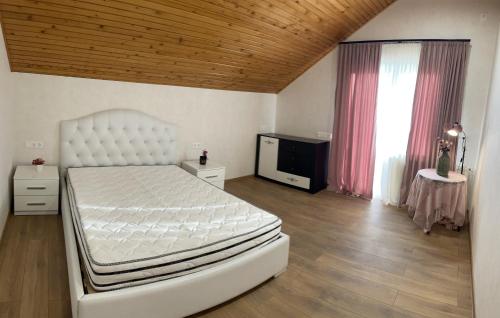ein Schlafzimmer mit einem großen weißen Bett und einem TV in der Unterkunft Vila Mtatsminda in Okrokana