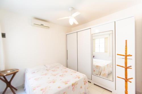a white bedroom with a bed and a mirror at HOSTEL DIKASA in Cuiabá
