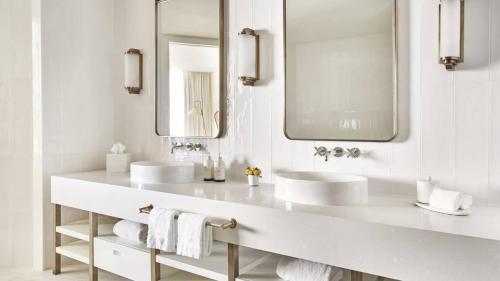a white bathroom with two sinks and two mirrors at Four Seasons Hotel and Residences Fort Lauderdale in Fort Lauderdale