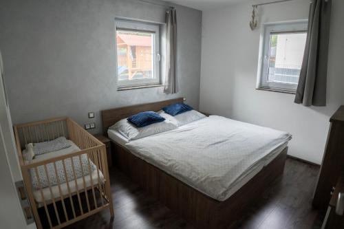 sypialnia z łóżkiem i łóżeczkiem dziecięcym oraz 2 oknami w obiekcie Chata Motýľ Oravská priehrada w mieście Lavkovo