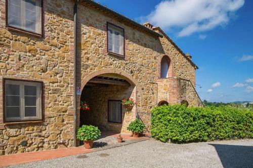 um edifício de pedra com dois vasos de plantas em frente em Borgo Collelungo apartments in Montaione em La Collina