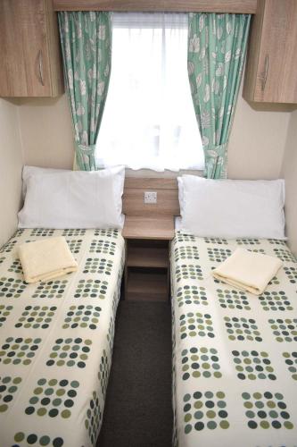 2 Betten in einem kleinen Zimmer mit Fenster in der Unterkunft Rio Gold SS10 in Minehead