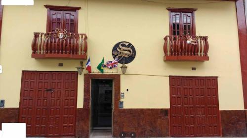 un edificio con puertas rojas y balcones. en Rosario Melchora Vásquez Rodriguez, en Cajamarca