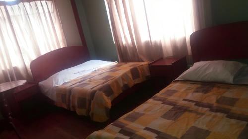 1 dormitorio con 2 camas y una ventana con cortinas en Rosario Melchora Vásquez Rodriguez, en Cajamarca