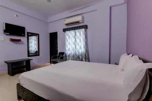 una camera da letto con un grande letto bianco e una finestra di Super OYO The Suncity Hotel a Patna