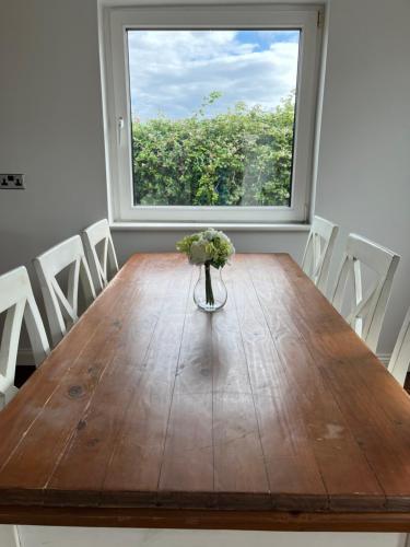 a vase of flowers on a wooden table in front of a window at Harbour View Cottage, Rochespoint, Cork Harbour in Midleton