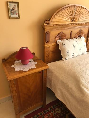 a bedroom with a bed with a red lamp on a table at Falubíró Vendégháza in Bekölce