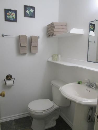 a white bathroom with a toilet and a sink at Edgewater Motel and Campground in Temiskaming Shores