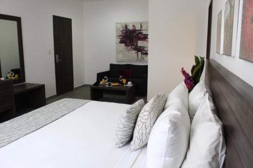 a bedroom with a white bed with pillows at Mesón de la Luna Hotel & Spa in Mérida