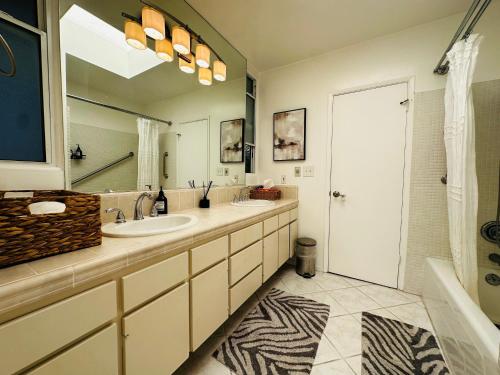 a bathroom with two sinks and a large mirror at Urban Oasis: Stylish Mid-Century Home in Weho in Los Angeles