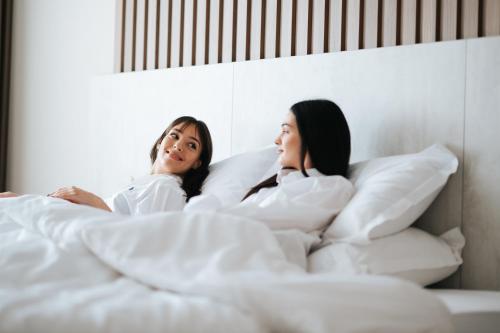 two women laying in bed under the sheets at Hotel Restaurant Kod Barića in Grude