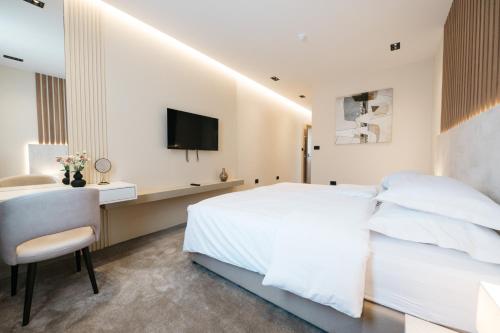 a white bedroom with a bed and a desk and a tv at Hotel Restaurant Kod Barića in Grude