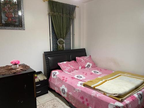 een slaapkamer met een bed met roze lakens en een raam bij Centre Sala Al Jadida in Oulad Yakoub
