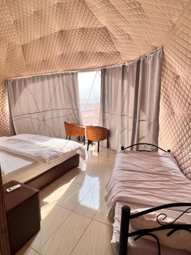 a bedroom with two beds and a large window at WADi RUM MAGIC CAMP in Wadi Rum