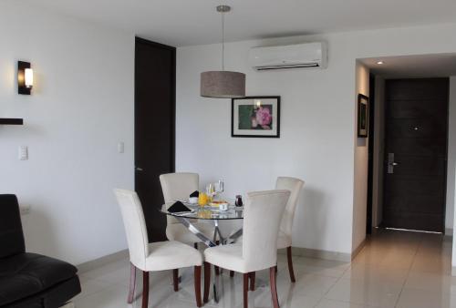 a dining room with a glass table and white chairs at Mesón de la Luna Hotel & Spa in Mérida