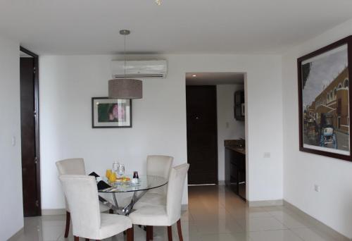 a dining room with a glass table and white chairs at Mesón de la Luna Hotel & Spa in Mérida