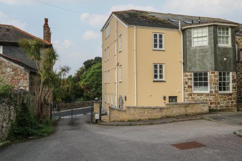 an old stone house with a fence and a palm tree at The Penthouse in Helston