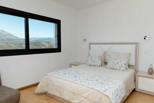 a white bedroom with a bed and a large window at Casa dos Mirtilos Duke T8 in Celorico de Basto