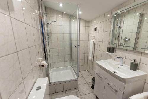 a bathroom with a shower and a toilet and a sink at Hotel Haus Biggen in Attendorn