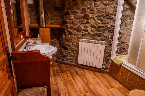 a bathroom with a sink and a stone wall at El Rincón de la Rosa in Brugos de Fenar