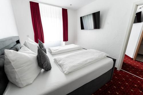 ein weißes Bett mit zwei Kissen im Schlafzimmer in der Unterkunft Hotel Haus Biggen in Attendorn