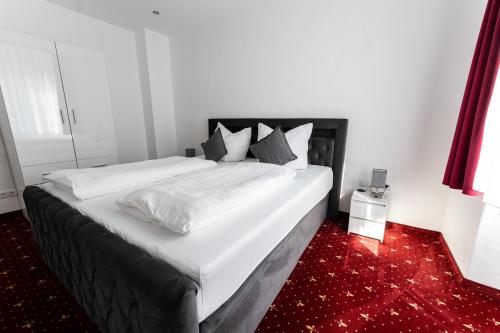 a bedroom with a large bed with white sheets and pillows at Hotel Haus Biggen in Attendorn