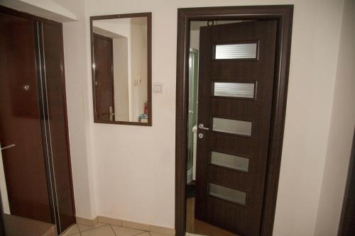 a bathroom with a wooden door and a mirror at Diana's Apartment in Braşov