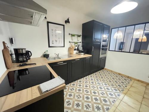 La cuisine est équipée d'un réfrigérateur noir et d'un évier. dans l'établissement Gite du vieux Morat, à Saint-Bonnet-Tronçais