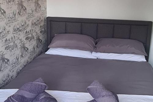 a bed with purple and white pillows on it at Runway Airbnb in Manchester