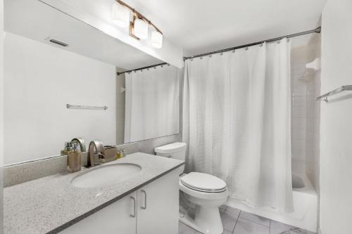 een witte badkamer met een toilet en een wastafel bij Modern 2-bedroom condo in Aventura in Aventura