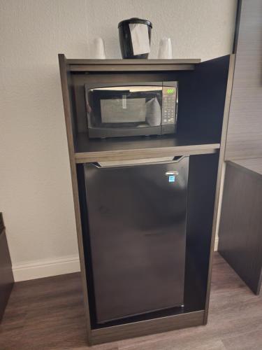 a microwave sitting on top of a stand with a refrigerator at Motel 6 Sacramento CA Natomas in Sacramento